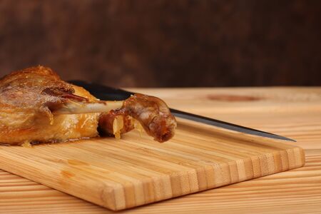Roast duck on bamboo cutting board with knifeの写真素材