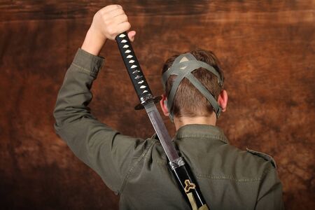 Man with gas mask and  katana sword on brown batik background