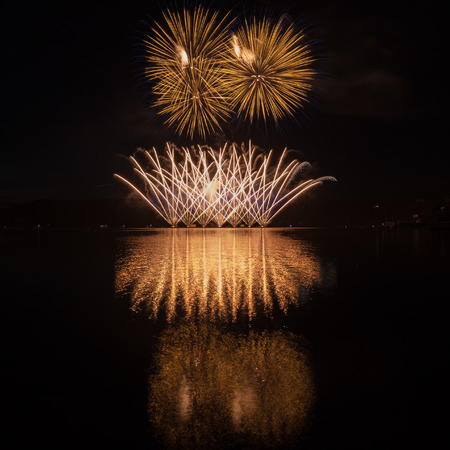 Colorful fireworks with reflection on lake and night sky in background.