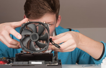 Young man installing CPU cooler fan on new, modern gaming motherboard.の写真素材