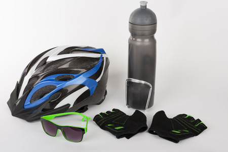Bike accessories, bike helmet, bike gloves, eyeglasses and water bottle in holder.の写真素材