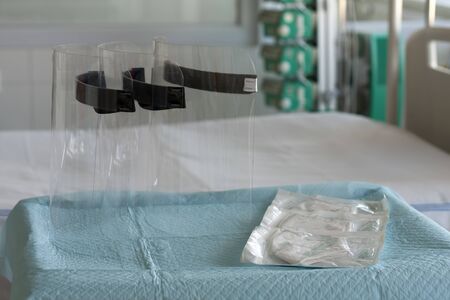 Three plastic protective shields and three respirators ffp2 on table in ICU in hospital, personal...