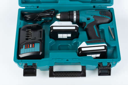 Cordless hammer screwdriver drill, battery charger and second battery in carry case on white...