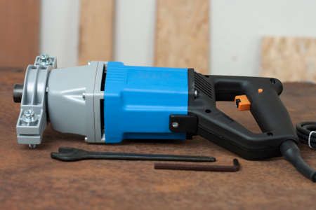 Wrench and mixing drill for mixing of mortar, paint, plaster and powder on old rusty metal sheet.