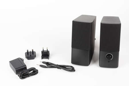 Two computer speakers on a white background. AC adapter with European plug and American plug and...