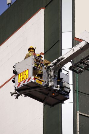 color photo of firefighter lifted in cherry picker in fire rescue