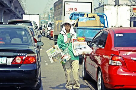 MANILA-APR. 9- Filipino newspaper boy selling newspapers in the traffic and busy  streets of the city of Metro Manila taken on April 29, 2010 in Manila, Philippines.のeditorial素材