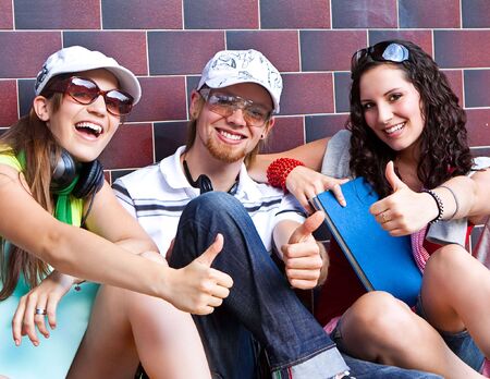 students are sitting beside a wall and making a rest