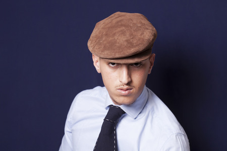 Handsome man wearing a brown beanie and a blue necktie and lookingの写真素材