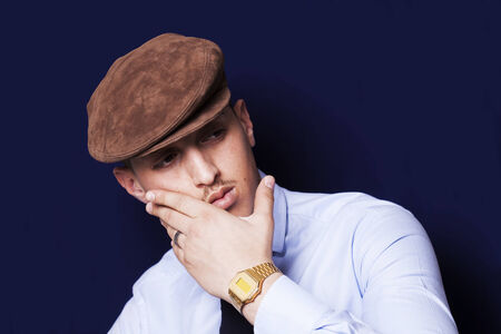 Handsome thoughtful man wearing a brown beanie and a blue necktieの写真素材