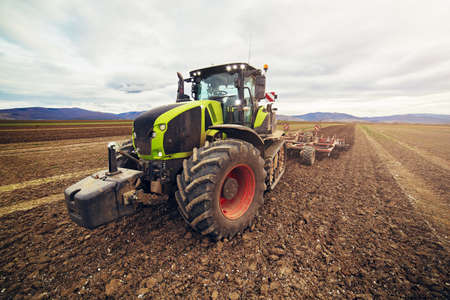 Modern tractor working on the field, modern agricultural transport, farmer working in the field, cultivation of land, agricultural machine concept.の写真素材