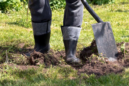 man working on a plot of galoshes with a spade
