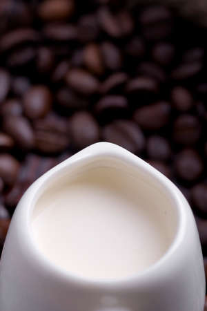 coffee creamer on the background of dark coffee beansの写真素材