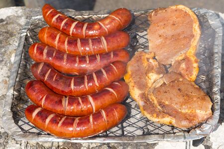 Grilled sausages and pork on the barbecueの写真素材