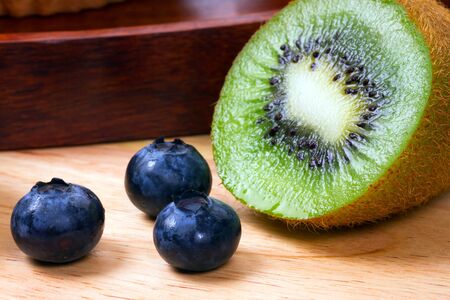 Blueberries and half of kiwi on kitchen boardの写真素材