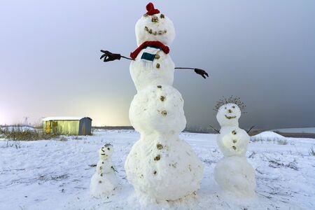 Snowman family in winter scenery at nightの写真素材