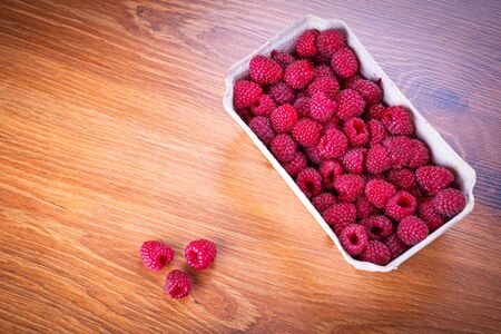 Ripe raspberries in the basket on wooden boardの写真素材
