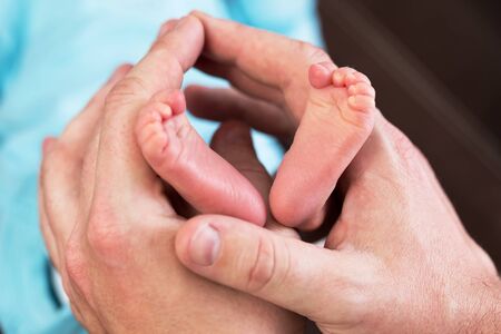 Newborn baby feet in father's handsの写真素材