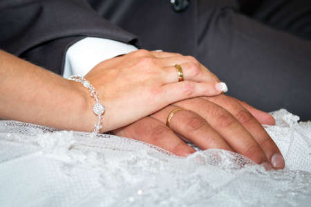 Married couple holding hands together with wedding ringsの写真素材