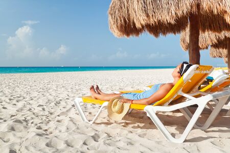 Woman relaxing under parasol on the beachの写真素材