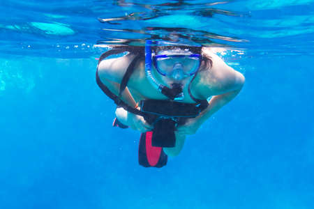 Woman snorkeling in the tropical water with an underwater cameraの写真素材