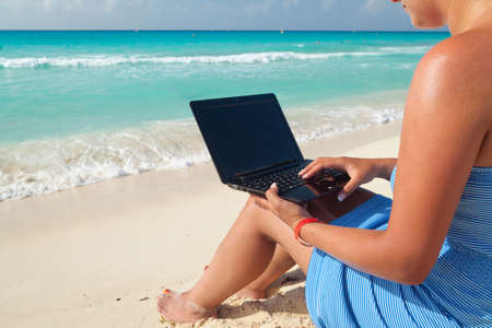 Woman relaxing with laptop on the beachの写真素材