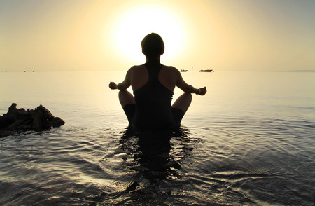 Woman in lotus pose at sunriseの写真素材