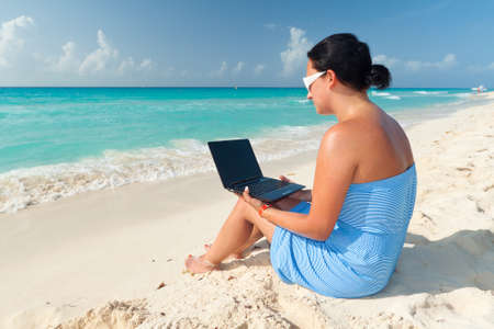 Woman relaxing with laptop on the beachの写真素材