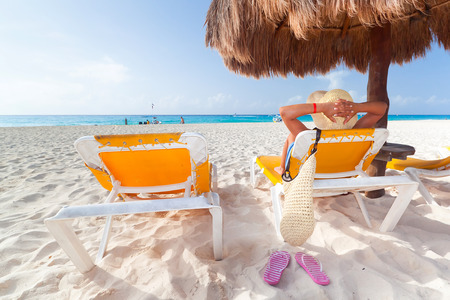 Woman relaxing under parasol on the beachの写真素材