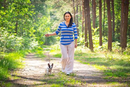 Beautiful woman walking her french bulldog puppyの写真素材