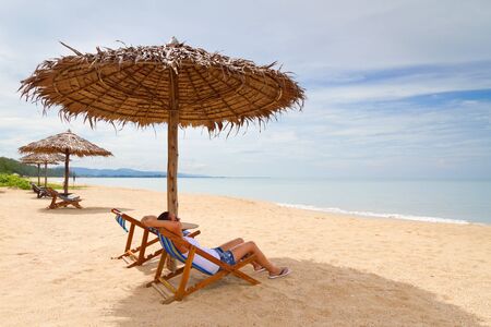 Woman relaxing under parasol on the beachの写真素材