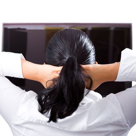 Woman resting hands behind her neck in front of the televisionの写真素材