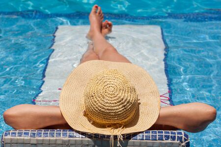 Woman in hat relaxing on swimming pool bedの写真素材