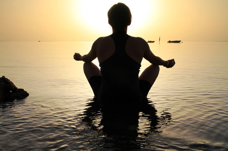 Woman in lotus pose at sunriseの写真素材