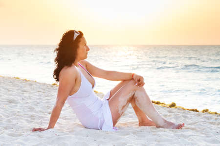 Beautiful woman relaxing on the beach during sunsetの写真素材
