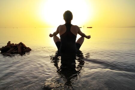 Woman in lotus pose at sunriseの写真素材