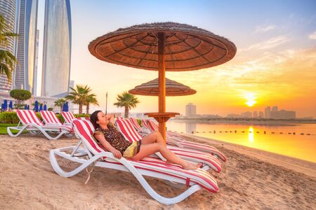Woman relaxing on deckchair at sunrise in Abu Dhabiの写真素材