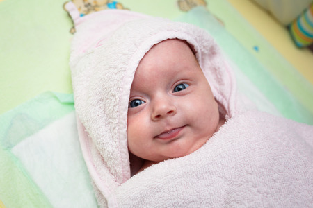Cute baby girl covered by pink towel after bathの写真素材