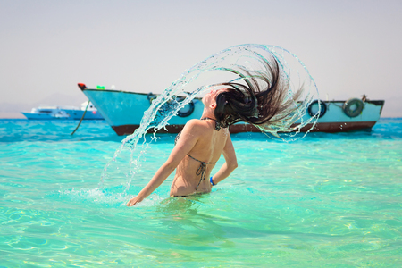 Young brunette emerging from the water with hair flipの写真素材