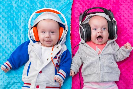 Happy twin babies listening to music on headphonesの写真素材