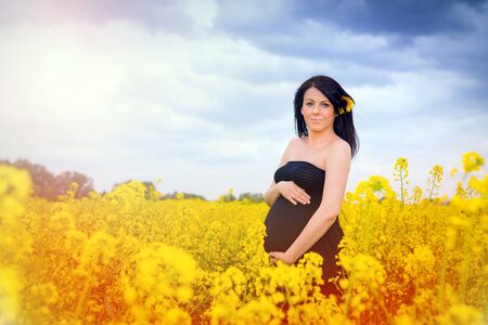 Beautiful pregnant woman in the rapeseed fieldの写真素材