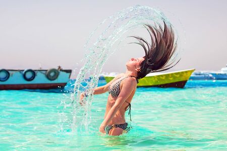 Young brunette emerging from the water with hair flipの写真素材