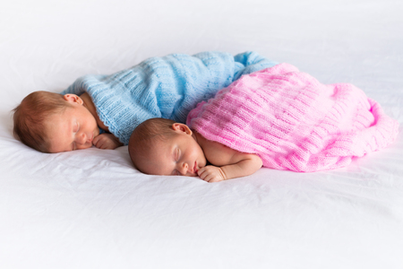 Baby boy and girl twins lying down in bedの写真素材