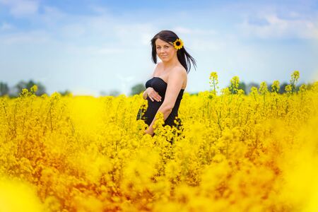 Beautiful pregnant woman in the rapeseed fieldの写真素材