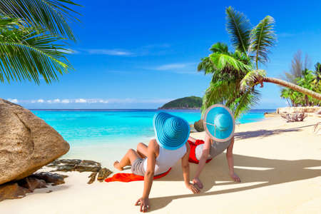 Two women with hats relaxing on the beachの写真素材