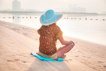 Woman at sunrise meditation on the beachの写真素材