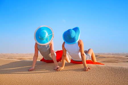Two women with hats relaxing at the desert safariの写真素材