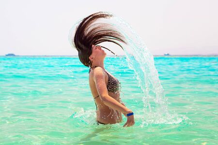 Young brunette emerging from the water with hair flipの写真素材
