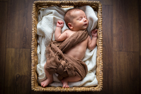 Newborn baby boy lying down inside the wicker basketの写真素材
