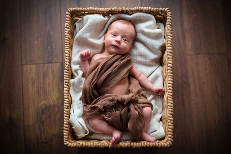 Newborn baby boy lying down inside the wicker basketの写真素材